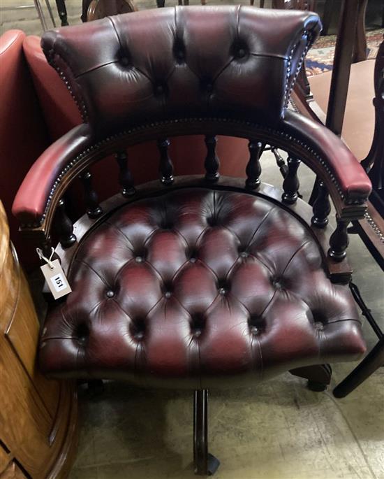 A reproduction tub shaped swivel desk chair upholstered in buttoned burgundy leather